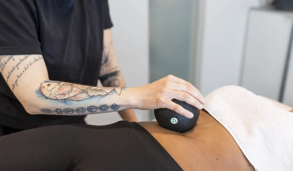 Physiotherapie Faszienball am Bauch einer Patientin